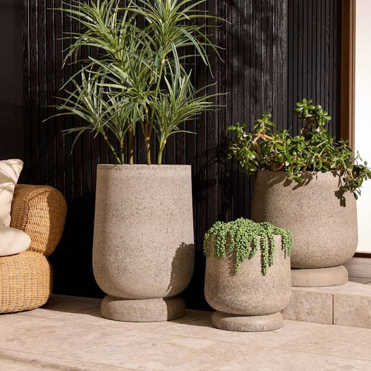 three cement planters sitting next to each other near a chair and potted plant