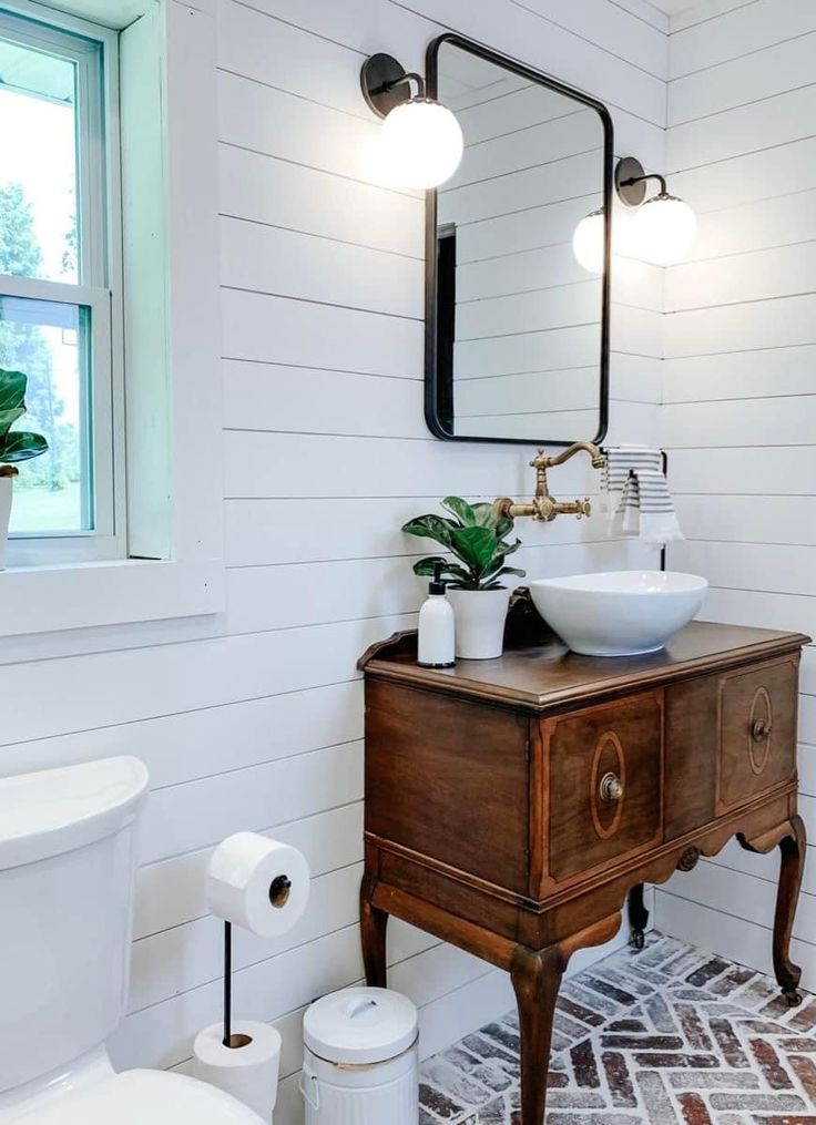 a bathroom with a sink, mirror and toilet paper roll on the floor next to it