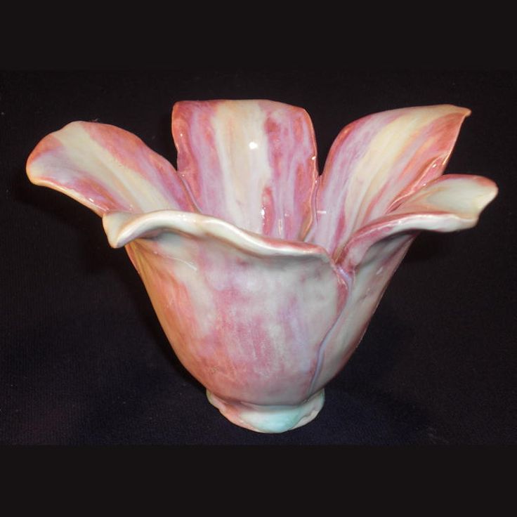 a pink and white vase sitting on top of a black table