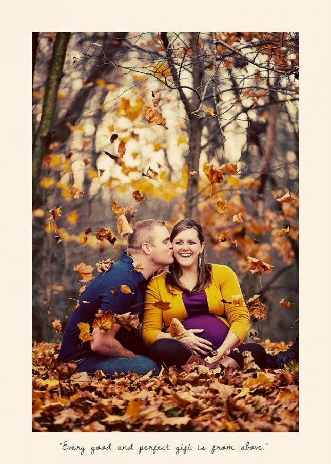 a man and woman sitting on the ground surrounded by leaves, posing for a photo