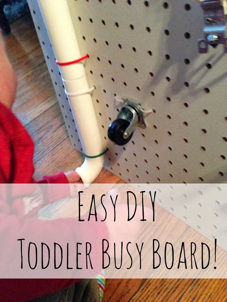 a toddler playing with a toy on the floor next to a wall mounted pegboard