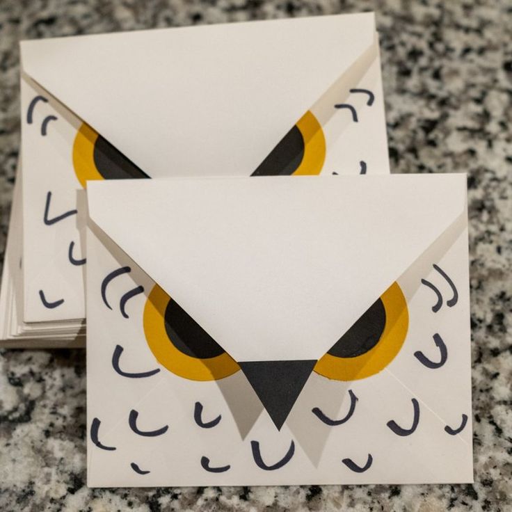 two folded envelopes with an owl design on them sitting on a marble counter top