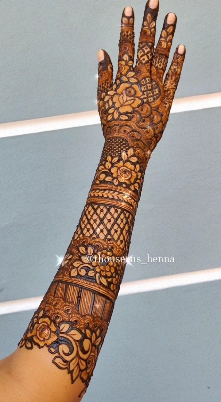 a woman's hand with henna tattoos on her arm and hands, showing the intricate