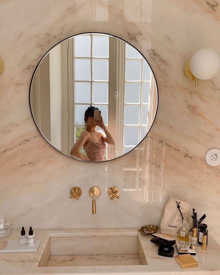 a woman taking a selfie in a bathroom mirror next to a sink and counter