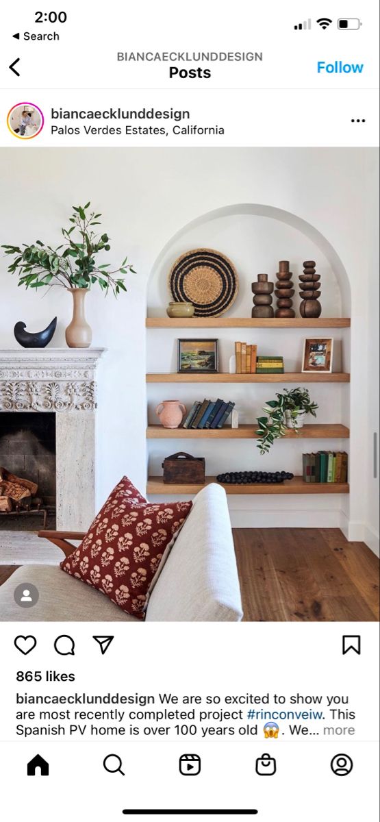 a living room with a fireplace and bookshelves on the wall, surrounded by wooden shelves