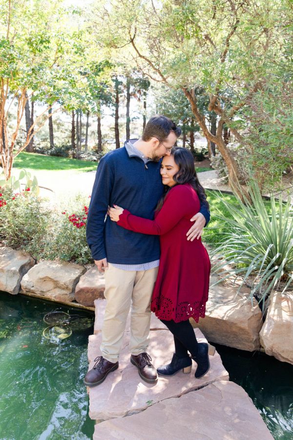 a man and woman standing next to each other on a rock in front of water