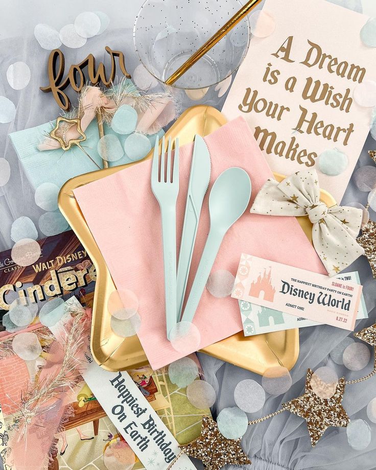 a table topped with pink napkins and silverware next to a sign that says a dream is a wish your heart makes