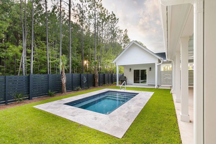 a pool in the middle of a yard with grass around it and trees on either side