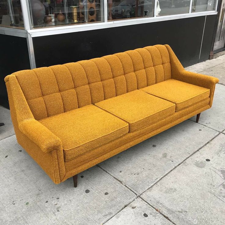 a yellow couch sitting on top of a sidewalk