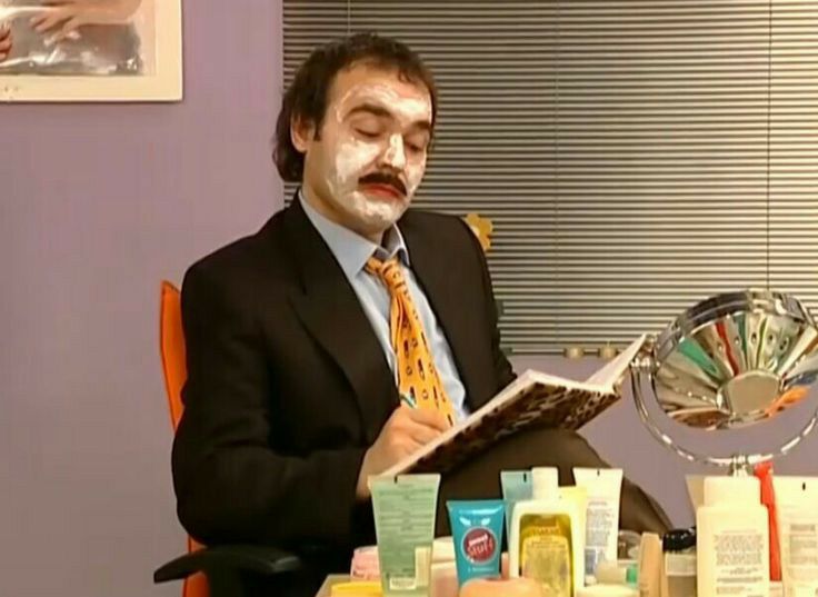 a man in a suit and tie is sitting at a table with some products on it