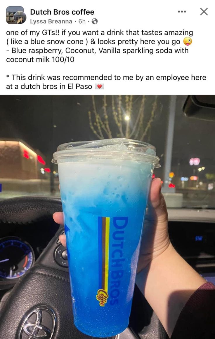 someone is holding up a blue drink in their hand and it looks like they are drinking something