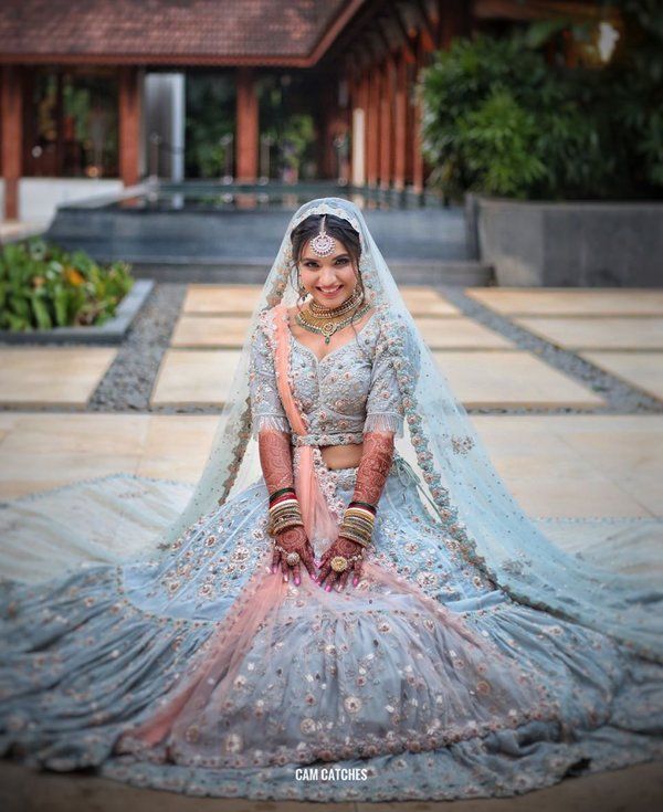 a woman in a blue and pink bridal gown sitting on the ground with her hands behind her back