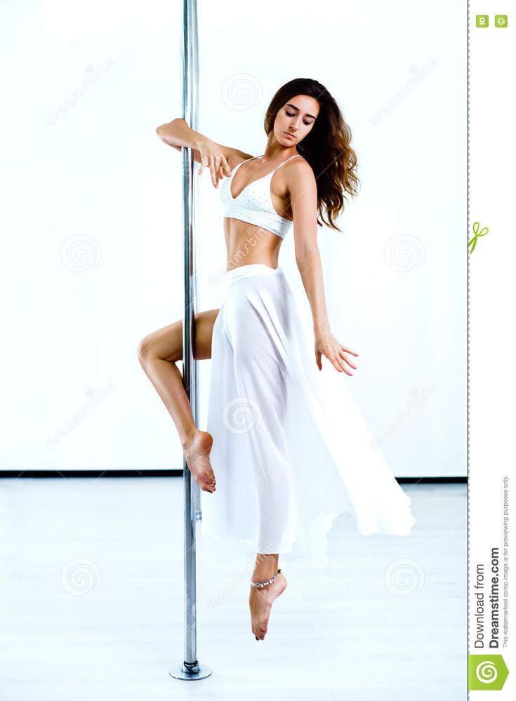 a beautiful woman in white is leaning on a pole and posing for the camera with her legs