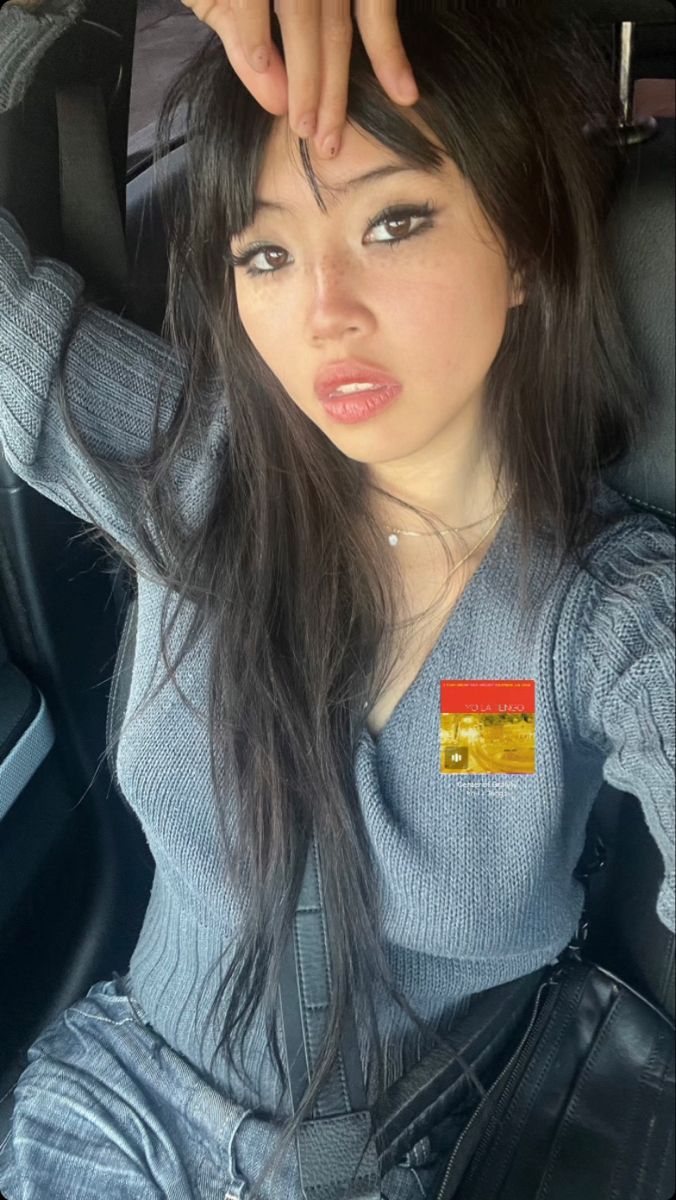 a woman with long hair sitting in the back seat of a car and holding her hand up to her head