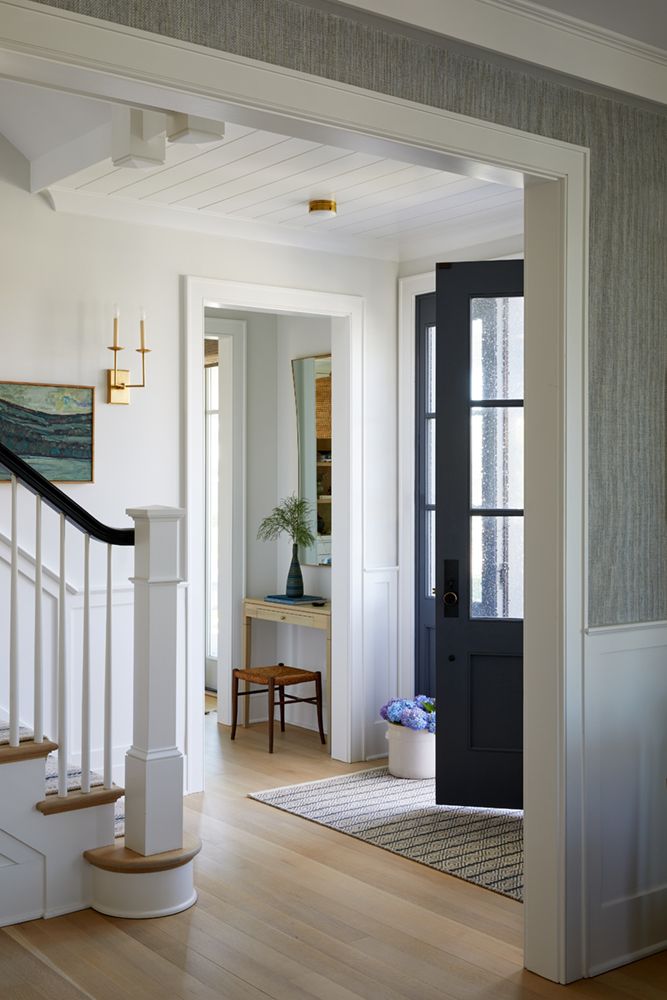 an open door leading to a living room and dining room with hardwood floors, white walls and black doors