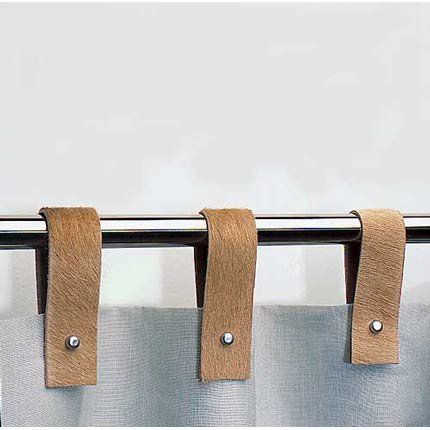 three pieces of brown leather hanging from a metal curtain rod with two clips attached to it