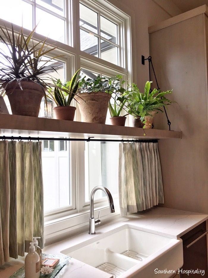 some plants are sitting on top of the window sill above a sink in a kitchen