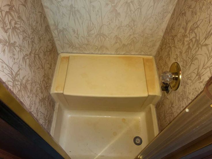 a small bathroom with a toilet and bathtub next to a wall papered wall