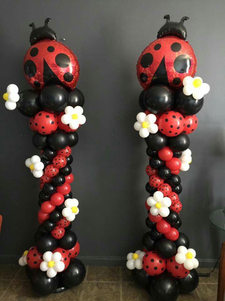 two tall ladybug balloons with flowers on them are standing next to each other