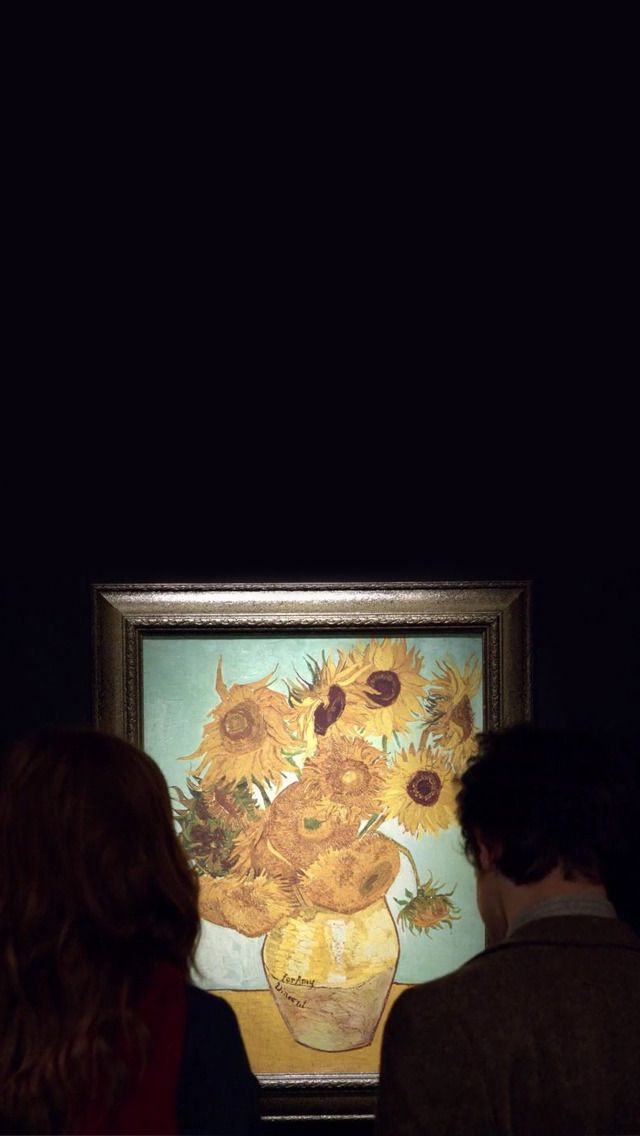 two people looking at an art work in a dark room with one person standing next to it