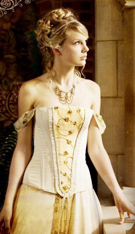 a woman in a white corset and gold dress standing next to a wall