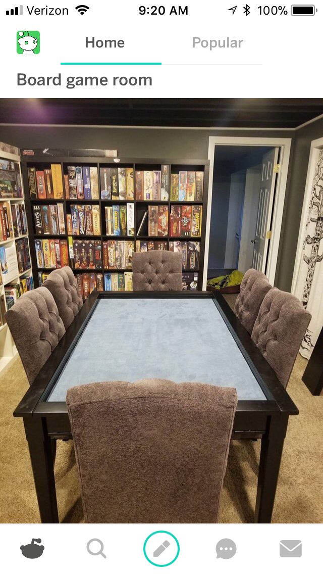 a table with some chairs around it in front of a book shelf filled with books