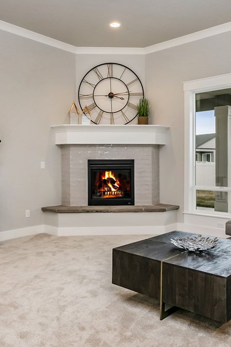 a living room with a fire place and large clock on the wall above it's fireplace