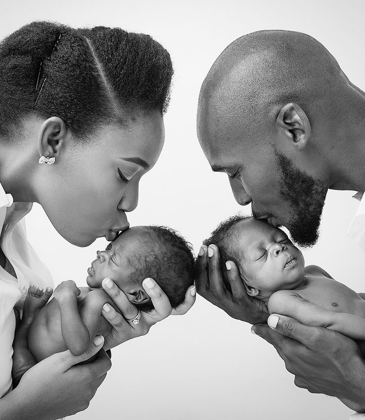 a man and woman are kissing their newborn baby's foreheads as they look at each other