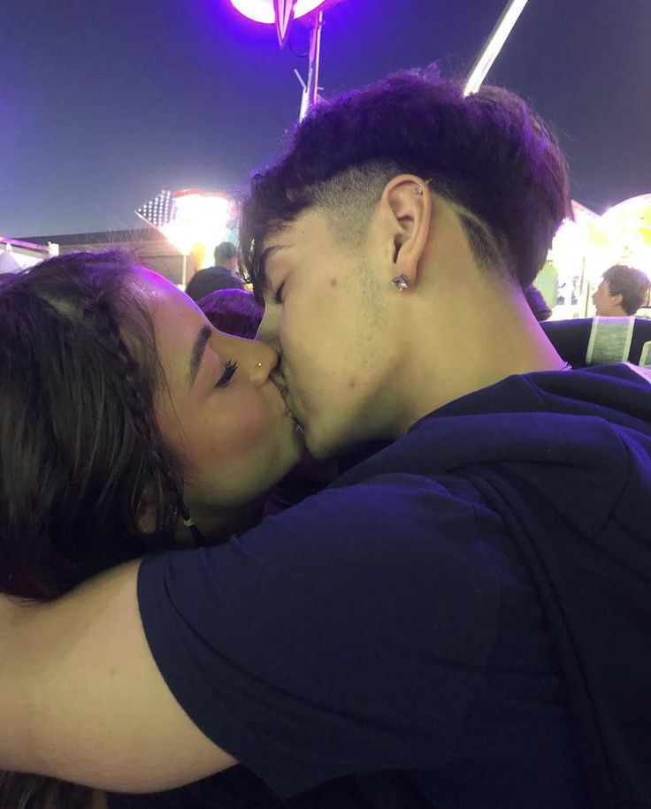 a man and woman kissing each other in front of a crowd at an outdoor event