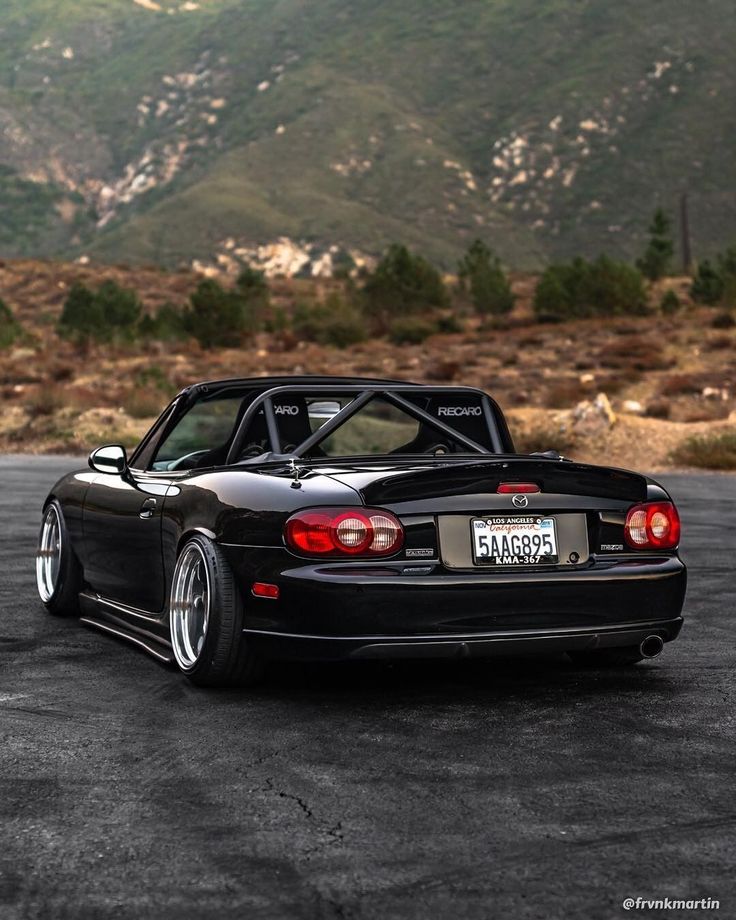 a black sports car parked in a parking lot with mountains in the backgroud