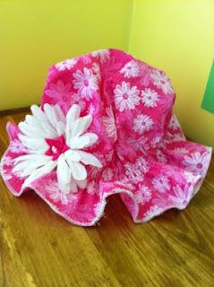 a pink and white flowered hat sitting on top of a wooden floor next to a wall