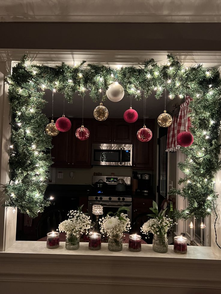 christmas decorations are displayed in front of a fireplace with candles and ornaments hanging from the mantle