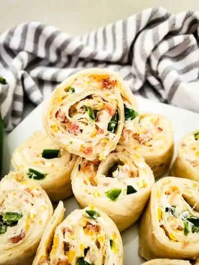 there are many rolls on the plate and one is filled with cheese, spinach and other ingredients