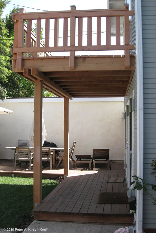 a wooden deck with chairs on it next to a house