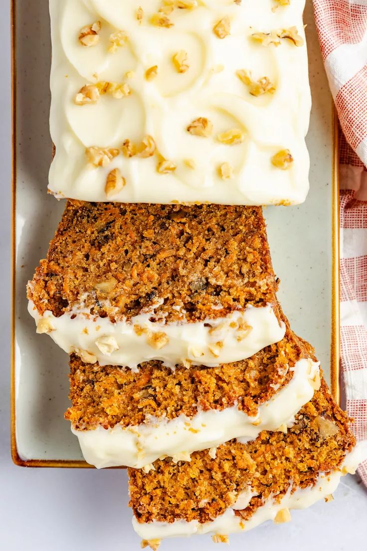 slices of carrot cake with cream cheese frosting on a white and yellow platter