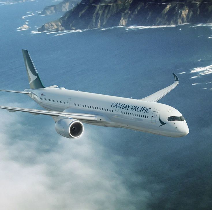 an airplane flying in the sky over some water and land with mountains in the background