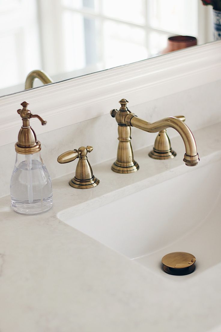 a bathroom sink with two faucets and a soap dispenser