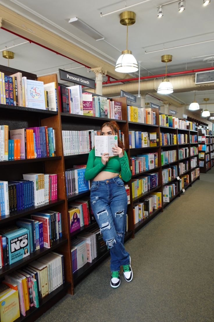 a woman standing in front of a bookshelf holding a book