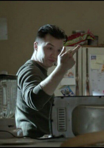 a man is pointing at something in the air with his hand while standing next to a microwave