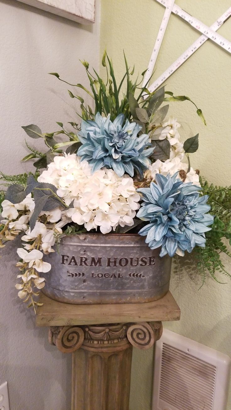 blue and white flowers are in an old metal bucket on a pedestal with the words farm house