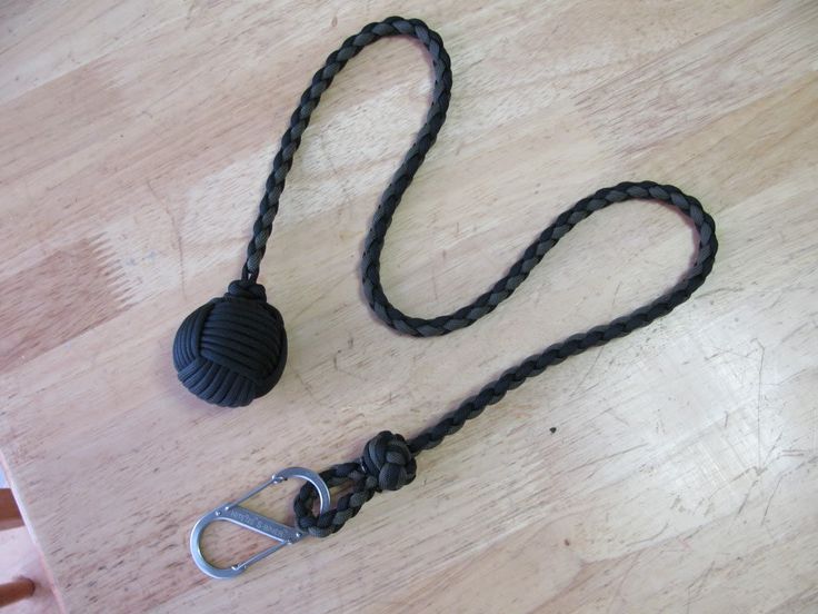 a black rope with a ball on it sitting on a wooden table next to a pair of scissors