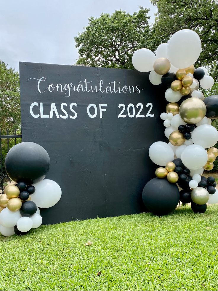 black and white balloons are arranged in front of a sign that says congratulations class of 202