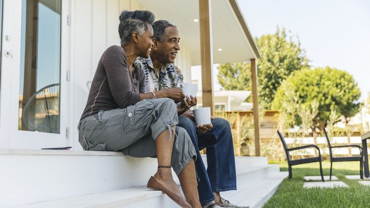 a man and woman sitting on the front steps of a house