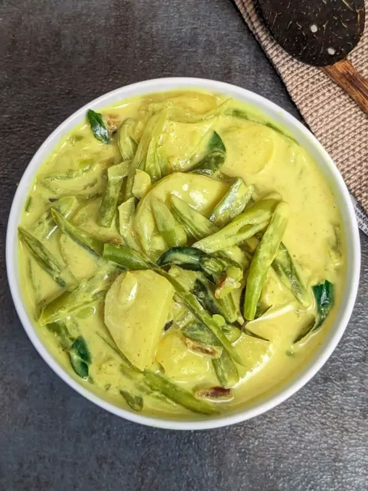 a white bowl filled with green vegetables and sauce