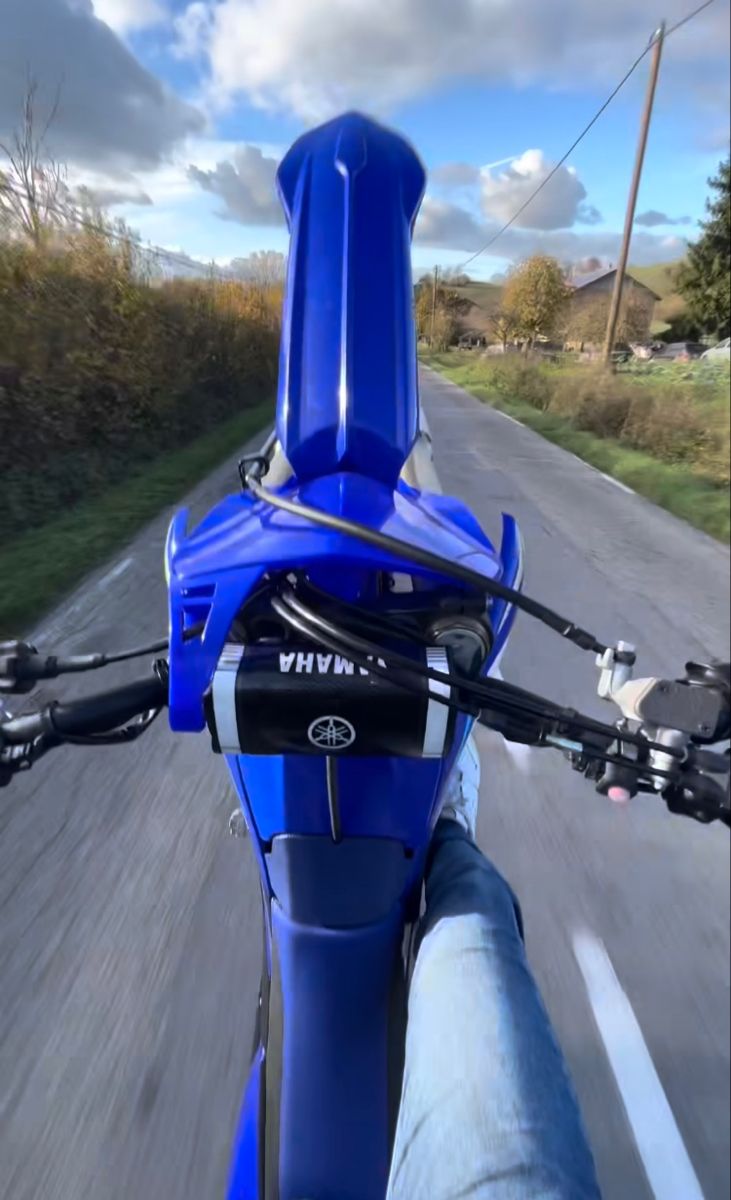 a person riding a blue motorcycle down a road