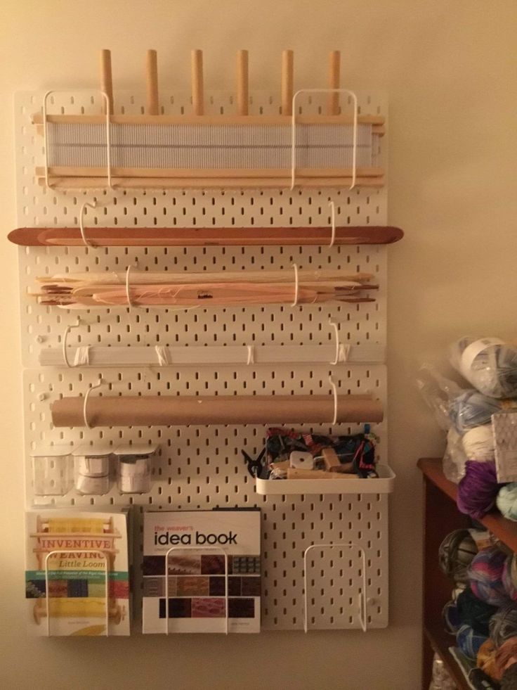 a peg board with yarn and knitting needles hanging from it's sides on a wall