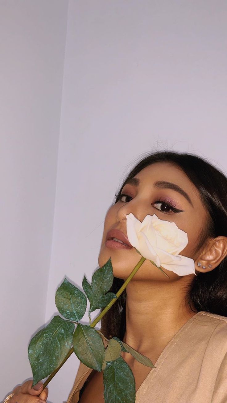 a woman holding a white rose up to her face