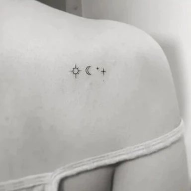 the back of a woman's shoulder with two stars and a moon on it