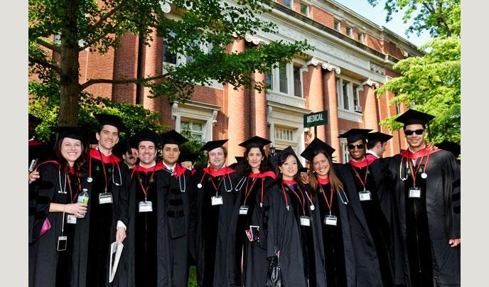 a group of people standing in front of a building wearing graduation gowns and caps