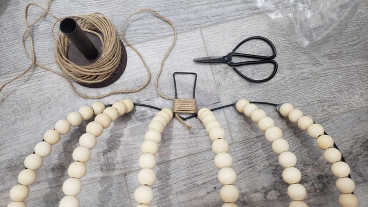 the beads are laid out on the table to make a necklace with scissors and string